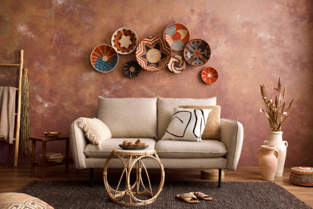 istock The stylish boho compostion at living room interior with design beige sofa, coffee table, stool wicker baskets and personal accessories. beige and white pillows. Cozy apartment. Template. 1410040659