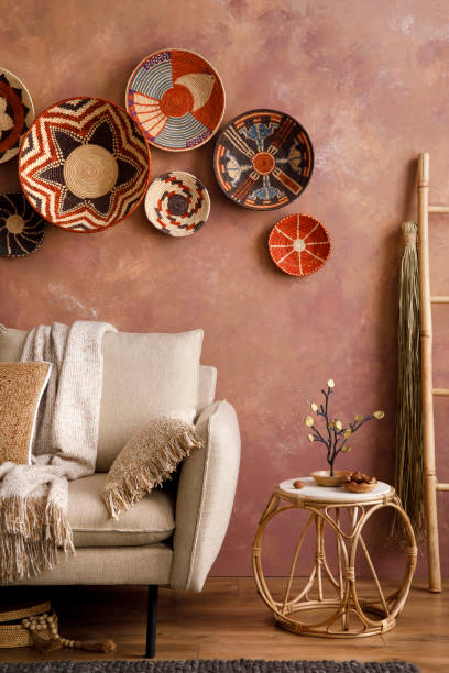 istock The stylish boho compostion at living room interior with design beige sofa, coffee table, stool wicker baskets and personal accessories. Brown and white pillows and plaid. Cozy apartment. Template. 1410040661