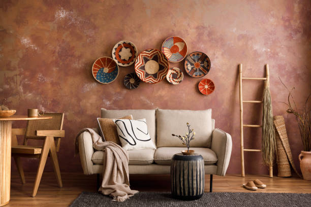 istock The stylish boho composition at living room interior with design beige sofa, coffee table, table, wicker baskets and personal accessories. Beige and white pillows. Cozy apartment. Template. 1410040663