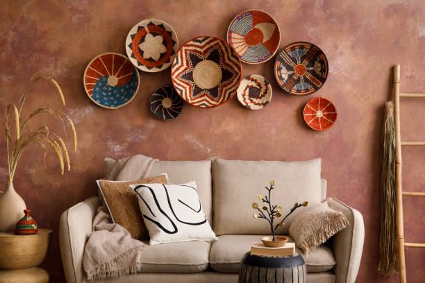 istock The stylish boho compostion at living room interior with design beige sofa, coffee table, stool wicker baskets and personal accessories. Brown and white pillows and plaid. Cozy apartment. Template. 1410040668