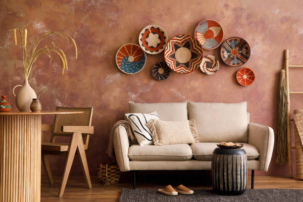 istock The stylish boho compostion at living room interior with design beige sofa, coffee table, stool wicker baskets and personal accessories. Brown and white pillows and plaid. Cozy apartment. Template. 1410040683
