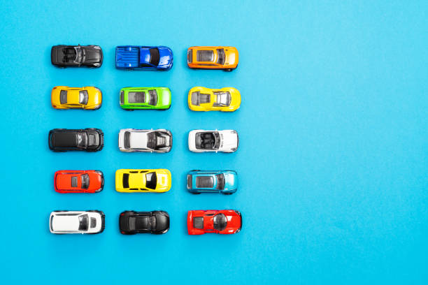 istock Multi colored toy cars lined up in rows on blue background with empty space, top view. 1410043514