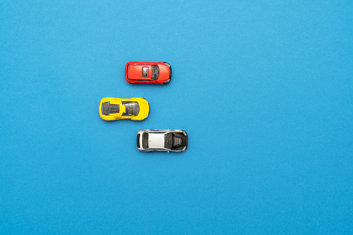 Three small rolling toy cars on blue background.