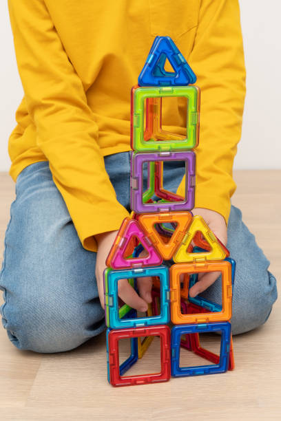 istock Boy assembling tower from colorful plastic pieces of magnetic construction set. 1410043545