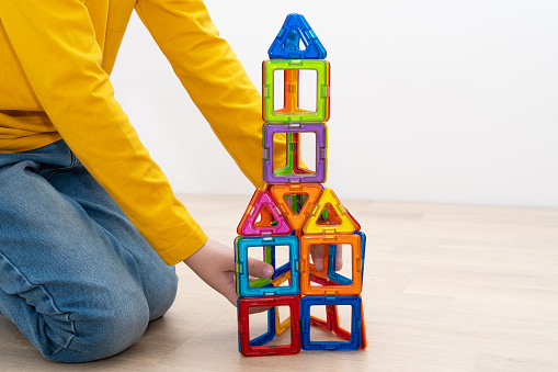 Shot of two young boys playing with building blocks in a room. Boys sitting on the floor and playing with toys alone.