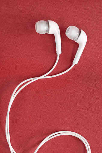 White wired earphones on red background