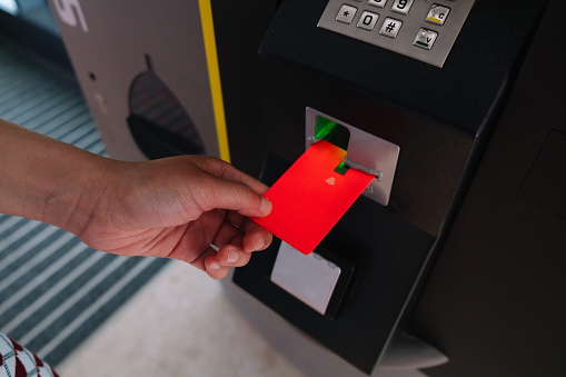 Woman hand is inserting card to atm machine to withdraw or transfer money - stock photo