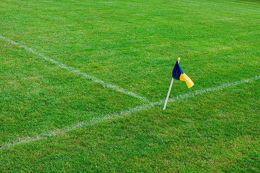 Blue yellow flag on a soccer field with green grass and white soccer field lines. The center line of the football field.