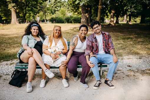 Friends posing while sitting on a bench in a public park