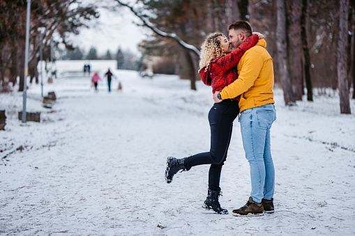 Beautiful young couple embracing in snowy park.