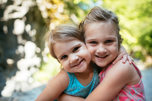 Two girls - sisters playing in summertime outdoors