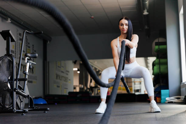 istock Athletic woman exercising with battle ropes at gym 1410055834