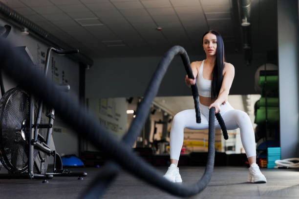 istock Muscular sportswoman doing gym exercises with rope 1410055975