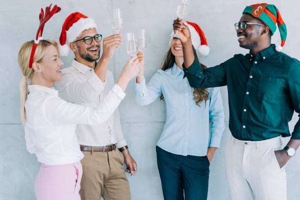 オフィスでのクリスマスのお祝いの間にシャンパンで乾杯しながら楽しみながら陽気なビジネスチーム。 - party business toast champagne ストックフォトと画像