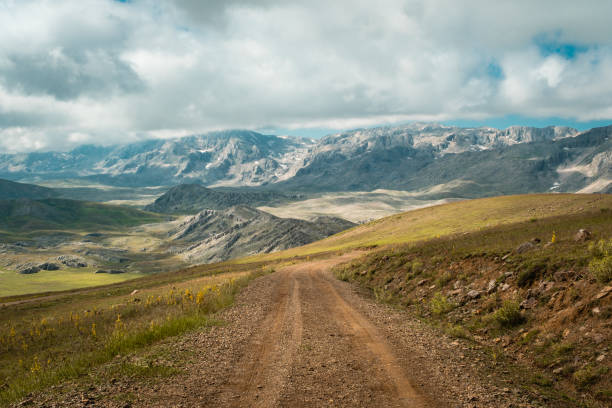 istock Dirt road mountain range cloud aerial view 1410057034