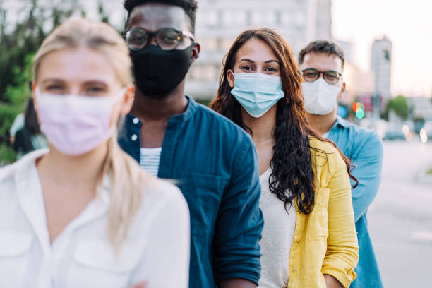istock People with protective face masks standing in line on the street. 1410057062