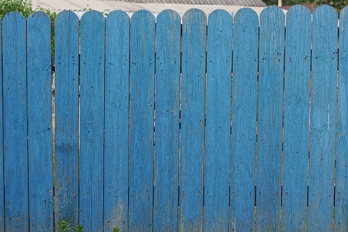 part of a blue rural fence wall made of wooden boards on the street