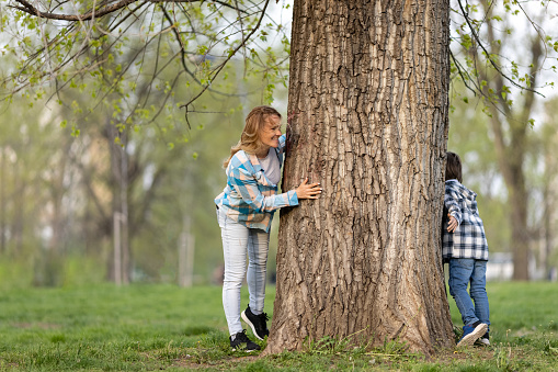 Happy mother playing hide and seek with son in public park