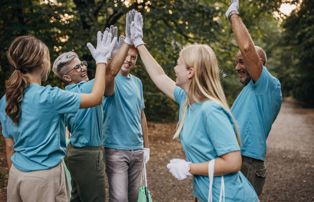 istock Happy community service volunteers cleaning up the park gathered around stacking hands 1410060970