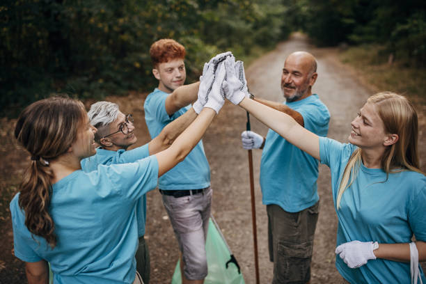 istock Happy community service volunteers cleaning up the park gathered around stacking hands 1410060997