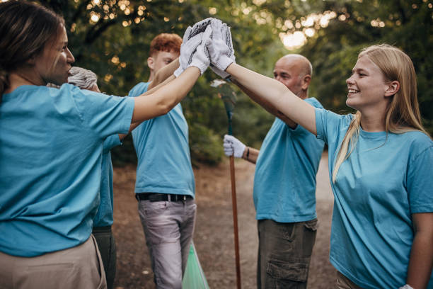 istock Happy community service volunteers cleaning up the park gathered around stacking hands 1410061132