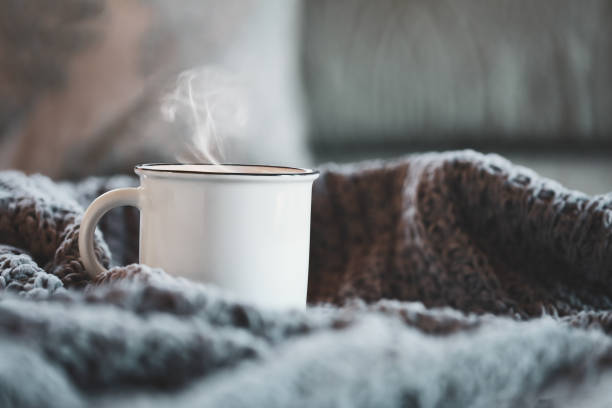istock Enamel Cup of Hot Steaming Coffee Sitting on a Cozy Bed 1410062690