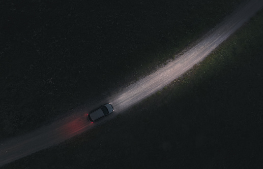 istock Aerial view of a car driving on a dirt country road at night 1410062736