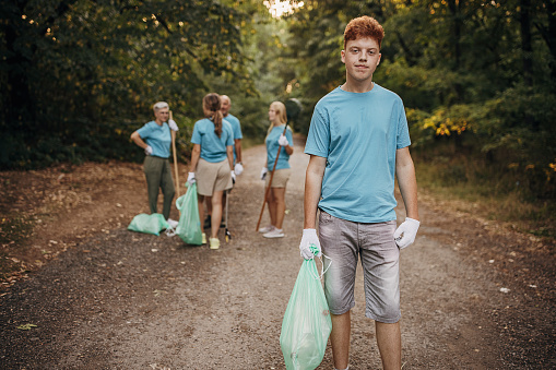 Portrait of young volunteer holding plastic bag in the nature