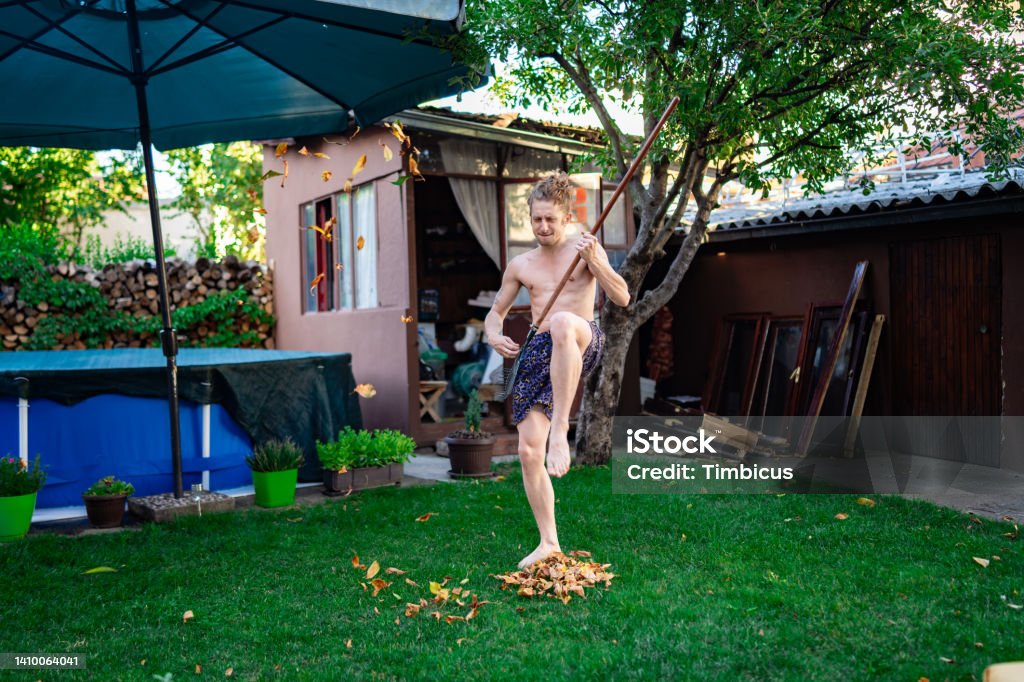 Rock'n'roll in the garden Caucasian ethnicity young adult man gardener playing rock'n'roll during raking old leaves. Adult Stock Photo