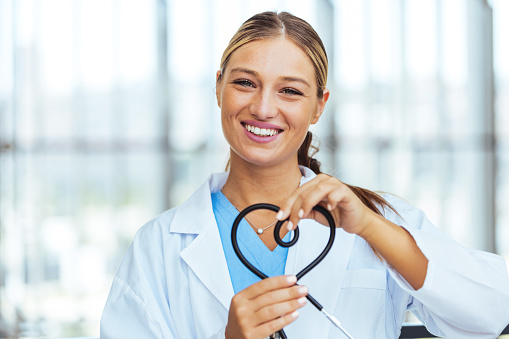 Female cardiologist doctor at the hospital smiling and making a heart shape