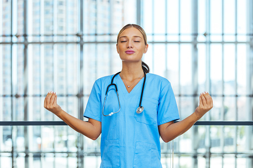 Beautiful young nurse woman wearing uniform and stethoscope at the clinic relax and smiling with eyes closed doing meditation gesture with fingers.