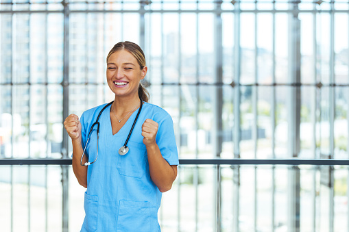 Professional nurse very happy and excited doing winner gesture with arms raised