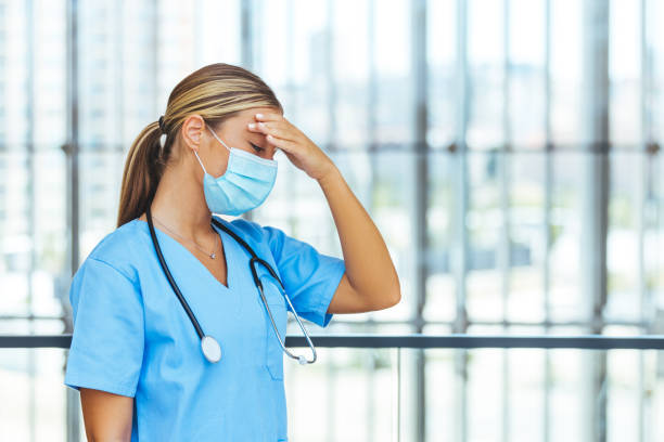 tired exhausted female nurse wears face mask and blue uniform - nurse hygiene emotional stress surgeon imagens e fotografias de stock