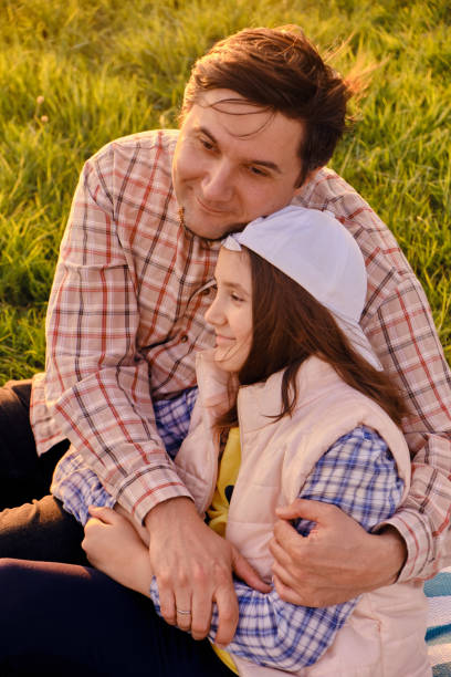 A happy father is having fun with his little daughter in nature, the daughter is hugging her dad and smiling.