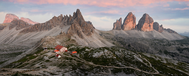 Stunning panoramic view of the Three Peaks of Lavaredo, (Tre cime di Lavaredo) Mount Paterno and a refuge during a beautiful sunset. The Three Peaks of Lavaredo are the undisputed symbol of the Dolomites, Italy.