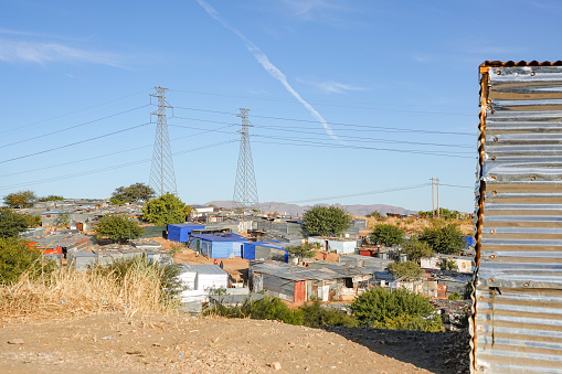 Shacks and stores with identifiable markers, as well as incidental people in the background, at Katutura Township near Windhoek in Khomas Region, Namibia