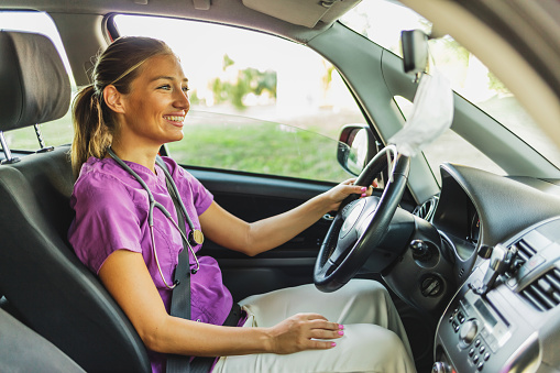 A confident female healthcare professional drives to work in a hospital or medical clinic. Nurse and healthcare workers.