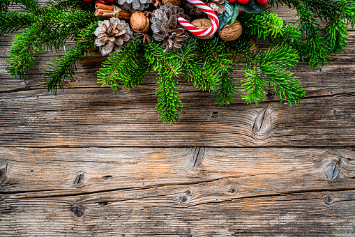 Overhead view of Christmas decoration arranged at the top of a rustic wooden table making a frame and leaving useful copy space.