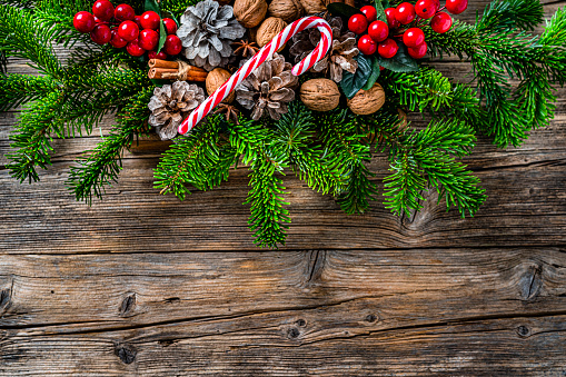 Overhead view of Christmas decoration arranged at the top of a rustic wooden table making a frame and leaving useful copy space.