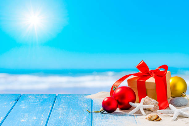 Christmas backgrounds: Christmas present, starfish, Christmas ornaments shot on sandy beach with defocused tropical beach at background. High resolution 42Mp outdoors digital capture taken with SONY A7rII and Zeiss Batis 40mm F2.0 CF lens