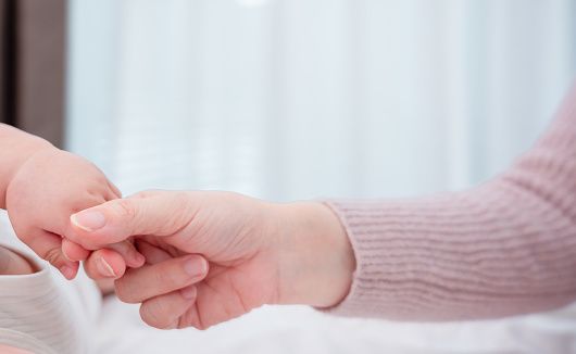 Hands holding of mother parent soft touch newborn baby fingers love family concept. Infant child portrait happy healthy.