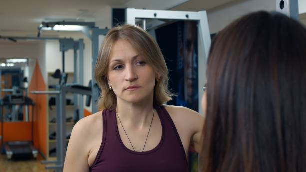 istock Two women in the gym are talking about the training process for burning fat. A personal trainer tells you how to eat and exercise to lose weight. Trainer woman in the gym leads a lecture. 1410078401