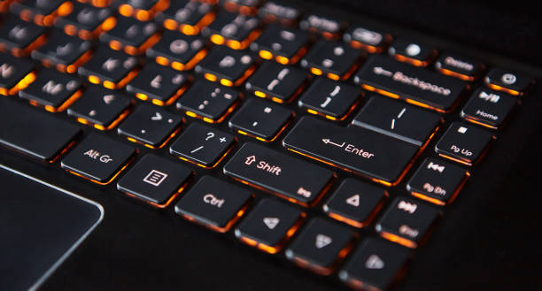 istock Close-up of a laptop keyboard with orange backlight. 1410080939