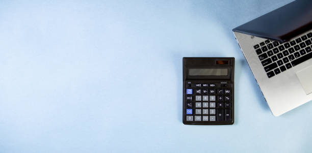 istock Flat lay of workspace with calculator and laptop on the blue background. 1410080955