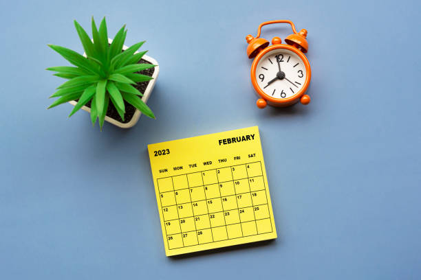 istock February 2023 calendar on Adhesive Note with alarm clock set at 8 o'clock. 1410084840