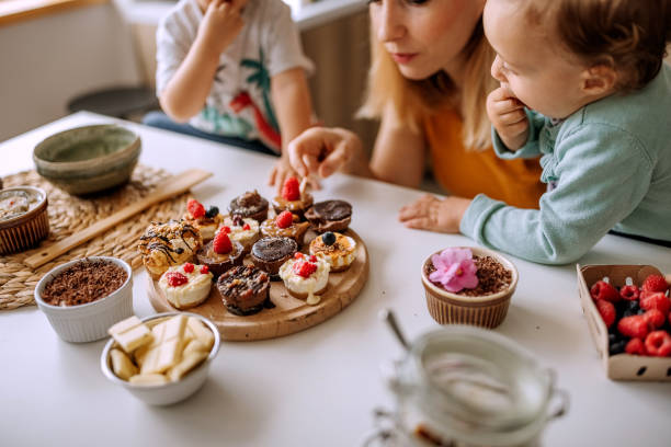 Our cute little mess Mother making cakes in kitchen with her small cute children family dependency mother family with two children stock pictures, royalty-free photos & images