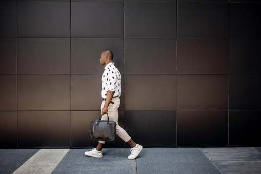 Young handsome businessman walking against black wall in a city