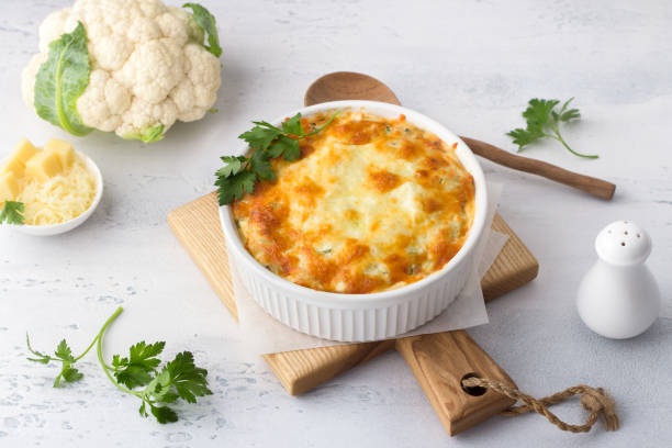 istock Homemade cauliflower casserole with cheese on a light gray background with ingredients. Delicious vegetarian food 1410097148