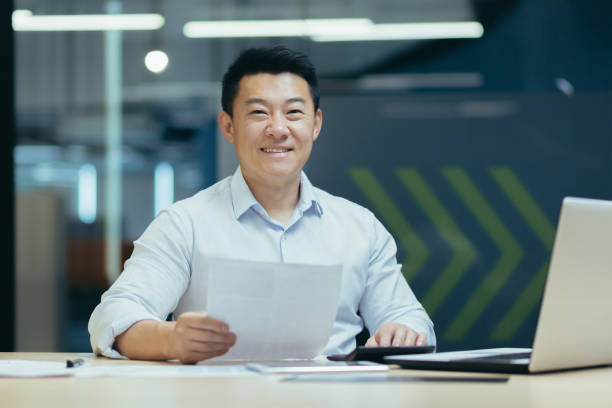 istock Portrait of successful asian boss, man with document in modern office 1410097192