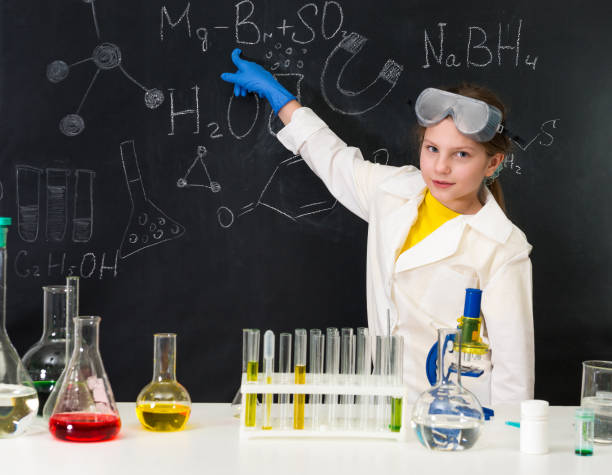 istock schoolgirl in chemistry lab pointing at formula on blackboard 1410097379